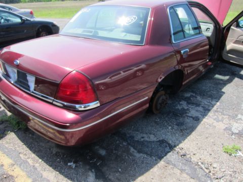 2001 Ford Crown Victoria - A maroon sedan, likely from the early 2000s, sits with its wheels removed.