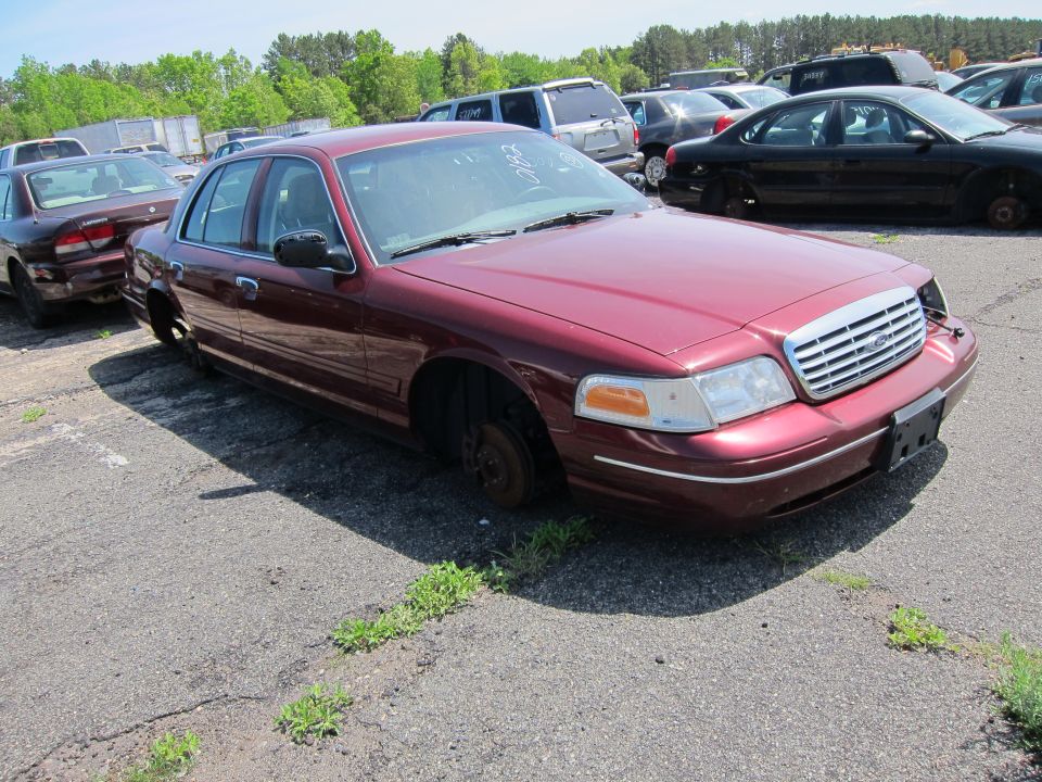 Maroon 2001 Ford Crown Victoria with missing wheels parked in a lot