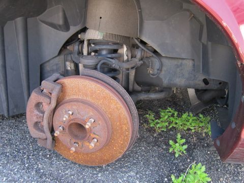 2001 Ford Crown Victoria - The vehicle's front suspension and brake system show significant rust.
