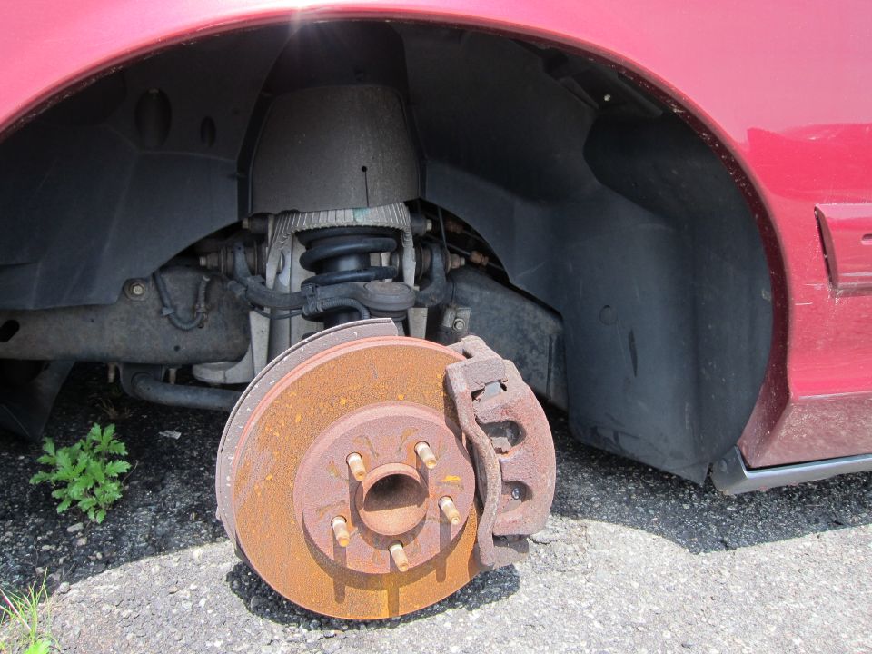 Red 2001 Ford Crown Victoria front wheel well with rusty brake rotor