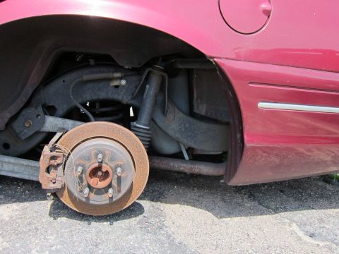 2001 Ford Crown Victoria - Close-up of a car's rear suspension and brake system, with visible rust on the rotor and exhaust.