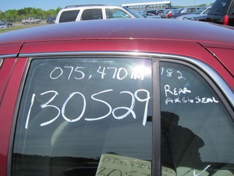 2001 Ford Crown Victoria - Chalk markings on the rear door window of a red sedan in a parking lot.