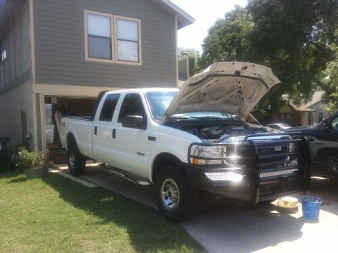 2004 Ford F-350 - White 2004 Ford F-350 crew cab pickup truck with its hood open, parked in a driveway.