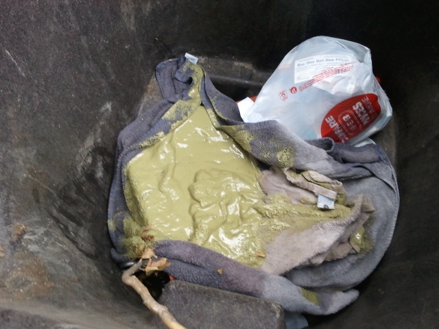 Trash can interior with towels and a green, viscous substance, a plastic bag is visible