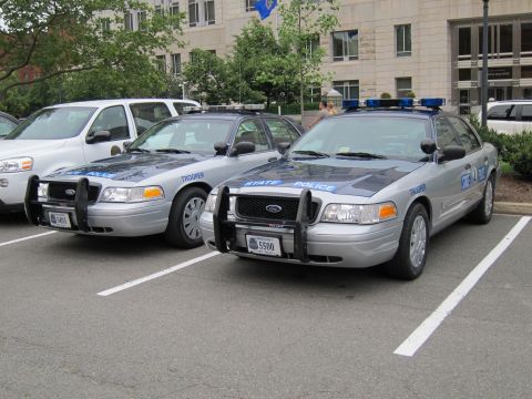 1991 Ford LTD Crown Victoria - Two silver Ford Crown Victoria State Police Trooper cars with push bars and lightbars parked in a lot.