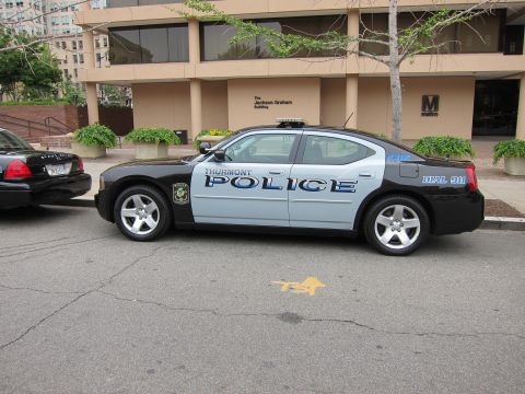 1991 Ford LTD Crown Victoria - black-and-silver Thurmont Police Dodge Charger parked next to another police car outside an office building.
