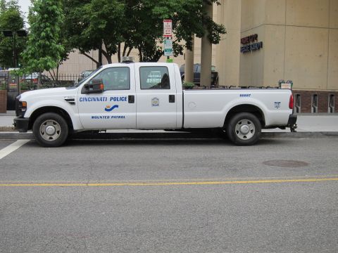 1991 Ford LTD Crown Victoria - white Cincinnati Police Mounted Patrol Ford Super Duty crew-cab pickup parked along a city street.