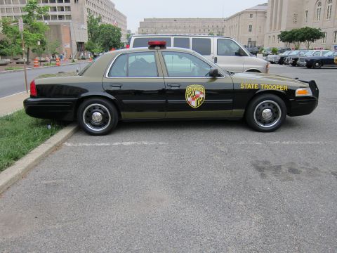 1991 Ford LTD Crown Victoria - Driver-side profile of a black Maryland State Trooper Ford Crown Victoria police cruiser parked on a downtown street.