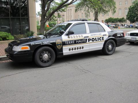 1991 Ford LTD Crown Victoria - black-and-white Terre Haute Police Ford Crown Victoria K-9 cruiser parked along a curb near brick buildings.