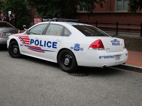 1991 Ford LTD Crown Victoria - Rear-quarter view of a white Chevrolet Impala marked Metropolitan Police 6th District with red-white-blue striping.