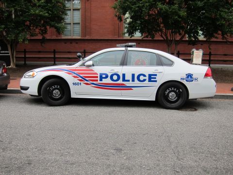 1991 Ford LTD Crown Victoria - Driver-side profile of a white Chevrolet Impala DC police cruiser with bold POLICE lettering and red-and-blue swoosh graphics.