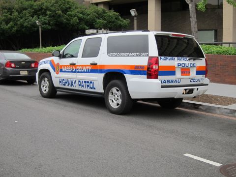 1991 Ford LTD Crown Victoria - Rear-quarter view of a white Nassau County Highway Patrol Chevrolet Suburban police SUV with orange and blue striping.