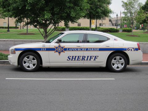 1991 Ford LTD Crown Victoria - Side profile of a white Dodge Charger sheriff car marked Lafourche Parish Sheriff parked along a street.