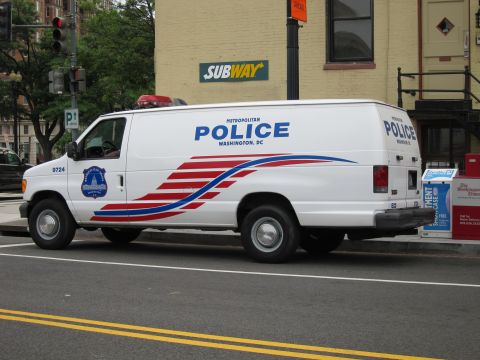 1991 Ford LTD Crown Victoria - white Ford Econoline Metropolitan Police DC cargo van parked at a corner curb near a Subway storefront.