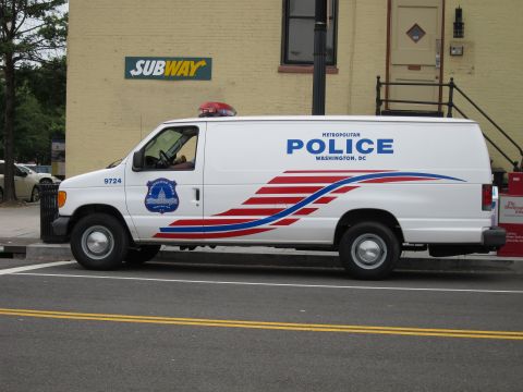 1991 Ford LTD Crown Victoria - white Ford Econoline Metropolitan Police DC van parked along a street outside a Subway shop.