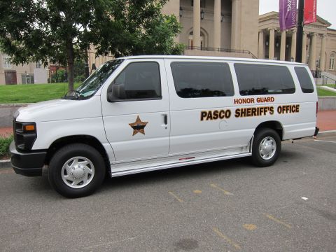 1991 Ford LTD Crown Victoria - white Ford Econoline passenger van lettered Pasco Sheriff's Office Honor Guard parked in a lot by a building.