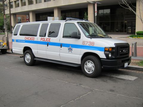 1991 Ford LTD Crown Victoria - white Ford Econoline van with blue stripe lettered Chicago Police parked along a city street.