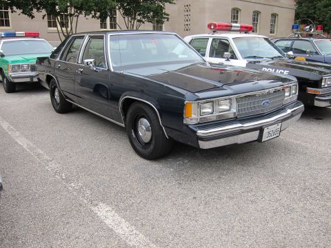 1991 Ford LTD Crown Victoria - dark blue Ford LTD Crown Victoria police sedan parked in a lot alongside other vintage patrol vehicles.