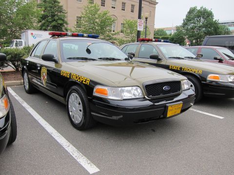 1991 Ford LTD Crown Victoria - black-and-tan State Trooper Ford Crown Victoria with push bar parked among other trooper cars in a lot.