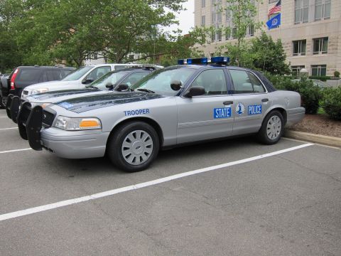 1991 Ford LTD Crown Victoria - silver State Police Ford Crown Victoria sedan with front push bar parked in a lot beside other vehicles.