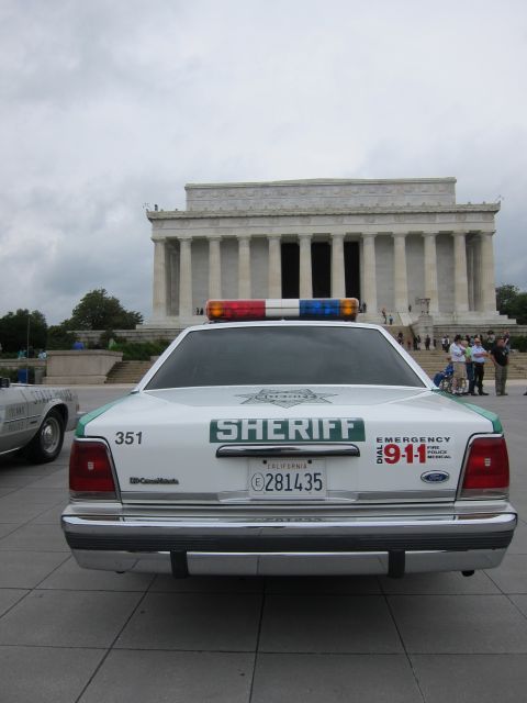 1991 Ford LTD Crown Victoria - green-and-white Sheriff patrol car, unit 351, parked at the Lincoln Memorial with its lightbar and 911 markings visible.