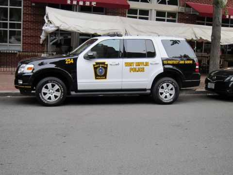 1991 Ford LTD Crown Victoria - black-and-white Ford Explorer marked West Mifflin Police To Protect and Serve, unit 254, parked along a city curb.