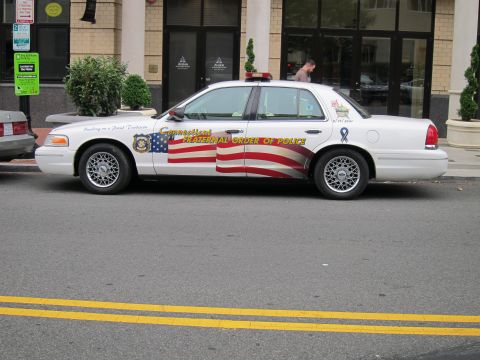 1991 Ford LTD Crown Victoria - white Ford Crown Victoria with American flag side graphics marked Connecticut Fraternal Order of Police, parked on a city street.
