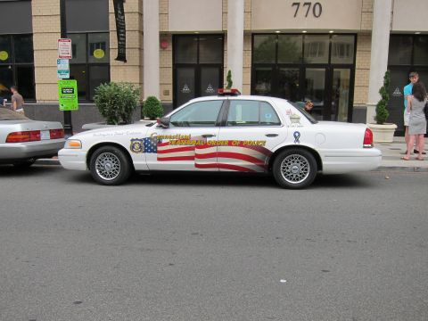 1991 Ford LTD Crown Victoria - white Ford Crown Victoria with American flag graphics marked Connecticut Fraternal Order of Police, parked by a building numbered 770.