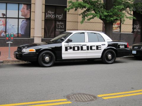 1991 Ford LTD Crown Victoria - black-and-white Ford Crown Victoria marked Hollywood Police with 911, parked at a city curb near a leasing storefront.