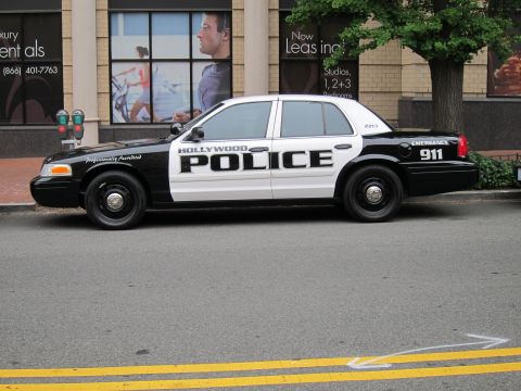 1991 Ford LTD Crown Victoria - black-and-white Ford Crown Victoria marked Hollywood Police, unit 2113, parked along a city street near a storefront.