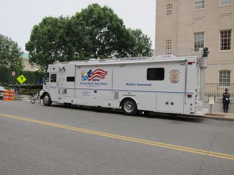 1991 Ford LTD Crown Victoria - large white United States Park Police Mobile Command truck with flag graphics parked along a street by a stone building.