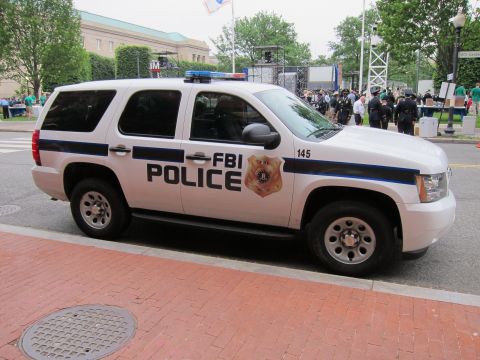 1991 Ford LTD Crown Victoria - white Chevrolet Tahoe marked FBI Police, unit 145, parked on a brick street with a crowd gathered behind.