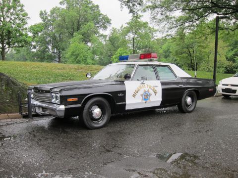 1991 Ford LTD Crown Victoria - Front three-quarter view of a vintage black-and-white Highway Patrol sedan with a front push bar on a wet road.