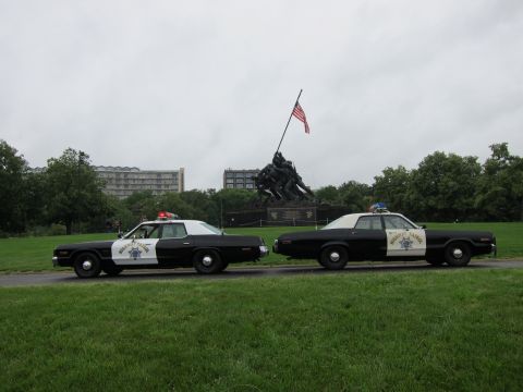1991 Ford LTD Crown Victoria - Two classic black-and-white Highway Patrol sedans parked along grass before the Iwo Jima Marine Corps War Memorial.