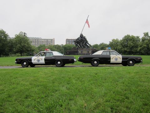 1991 Ford LTD Crown Victoria - Two vintage black-and-white Highway Patrol sedans lined up on grass before the Iwo Jima Marine Corps War Memorial.