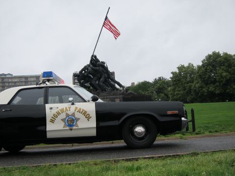 1991 Ford LTD Crown Victoria - Close side view of a black-and-white Highway Patrol sedan with door shield parked before the Iwo Jima War Memorial.
