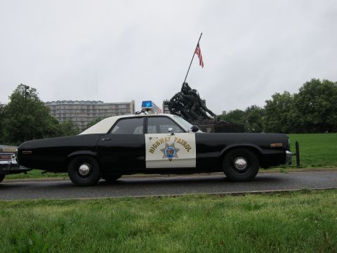 1991 Ford LTD Crown Victoria - Profile of a black-and-white Highway Patrol sedan with door shield parked on grass before the Iwo Jima War Memorial.