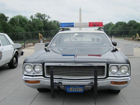 1991 Ford LTD Crown Victoria - Head-on view of a black-and-white Dodge police sedan with push bar and lightbar, Washington Monument visible in the background.