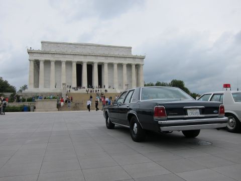 1991 Ford LTD Crown Victoria - dark blue Ford sedan parked at the Lincoln Memorial plaza with visitors walking near the steps.