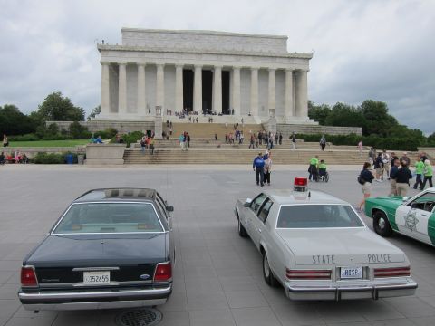 1991 Ford LTD Crown Victoria - dark sedan, white STATE POLICE cruiser and a green-and-white car lined up before the Lincoln Memorial.