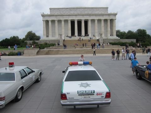 1991 Ford LTD Crown Victoria - white SHERIFF cruiser parked on the plaza in front of the Lincoln Memorial with a scattered crowd.