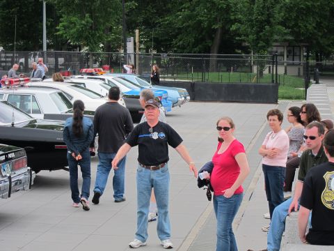 1991 Ford LTD Crown Victoria - group of people stand and talk on a plaza with a row of police cruisers parked behind them.