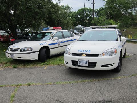 1991 Ford LTD Crown Victoria - Two white Chevrolet Impala police cars marked Police parked side by side on a paved lot.