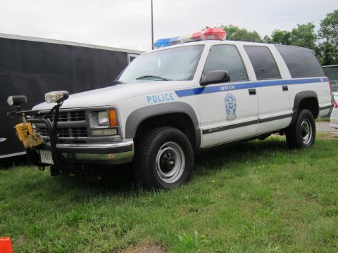 1991 Ford LTD Crown Victoria - white and gray Chevrolet Suburban police SUV marked Aviation with front brush guard parked on grass.