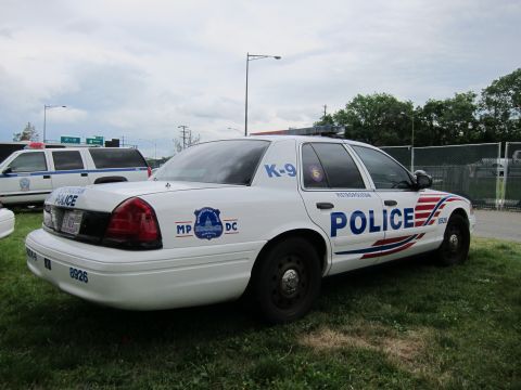 1991 Ford LTD Crown Victoria - white Ford Crown Victoria marked Police K-9 with the MPDC stripe parked on grass near a fence.