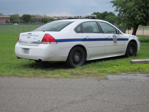 1991 Ford LTD Crown Victoria - white Chevrolet Impala marked United States Park Police with a blue stripe parked on grass.