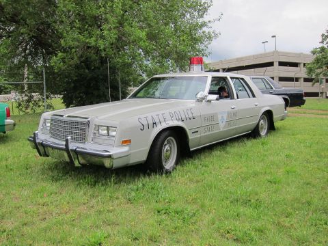 1991 Ford LTD Crown Victoria - silver State Police sedan marked Rhode Island State Police with a red roof light parked on grass.