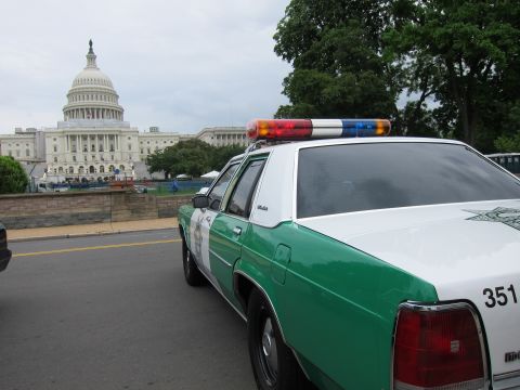 1991 Ford LTD Crown Victoria - green-and-white Sheriff patrol car with a multicolor roof lightbar is parked in front of the U.S. Capitol dome.