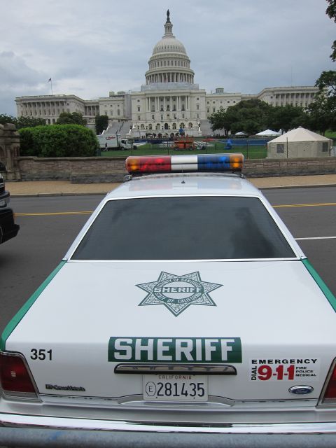1991 Ford LTD Crown Victoria - Rear view of a white Sheriff patrol car showing a seven-point star badge, Ford emblem and California plate, facing the U.S. Capitol.