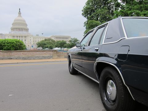 1991 Ford LTD Crown Victoria - dark four-door sedan photographed from low and behind, with the U.S. Capitol dome across the street.